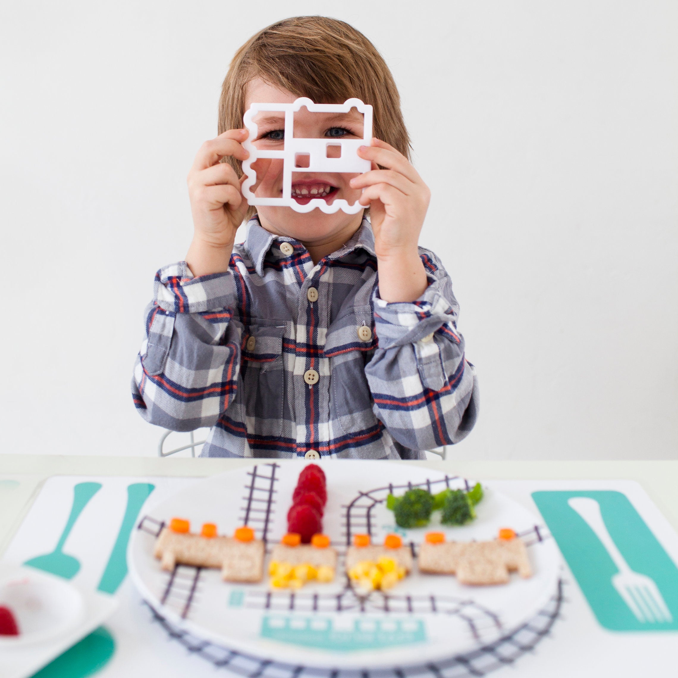 Little Boy playing with his Dylbug Train plate and Train Food Cutter - fun at mealtime for every train loving kid, even for picky eaters