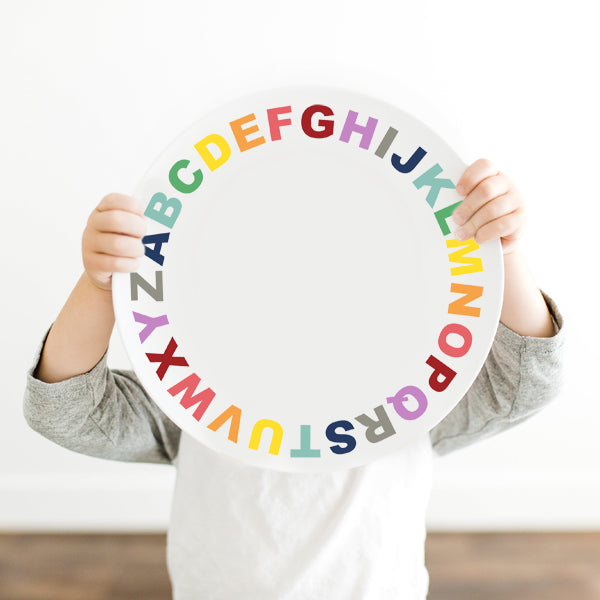 Little Boy holding the Dylbug Alphabet plate for kids