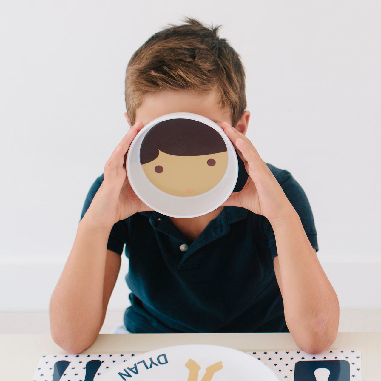 Little boy holding up his Dylbug personalized little me bowl with brown hair and eyes.
