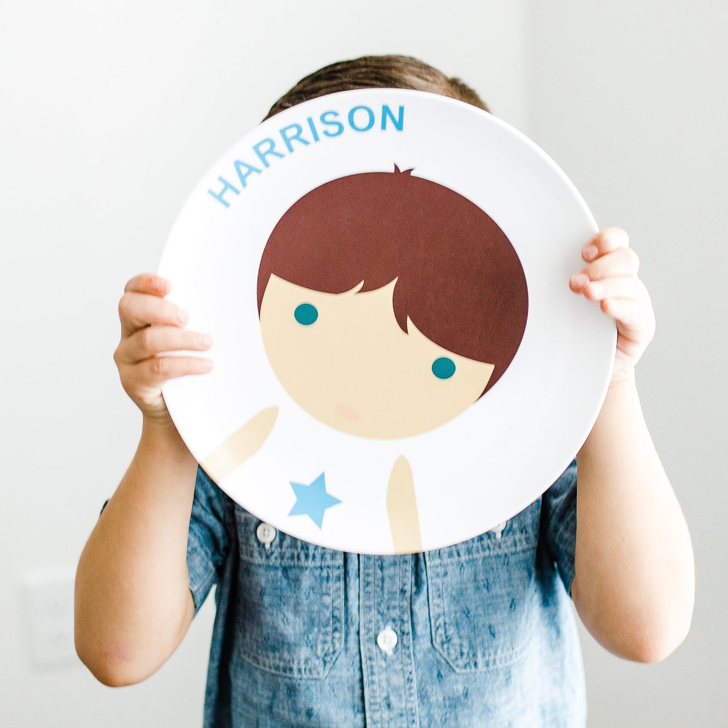 Little Boy holding up his Dylbug personalized Little Me Face Plate in blue.