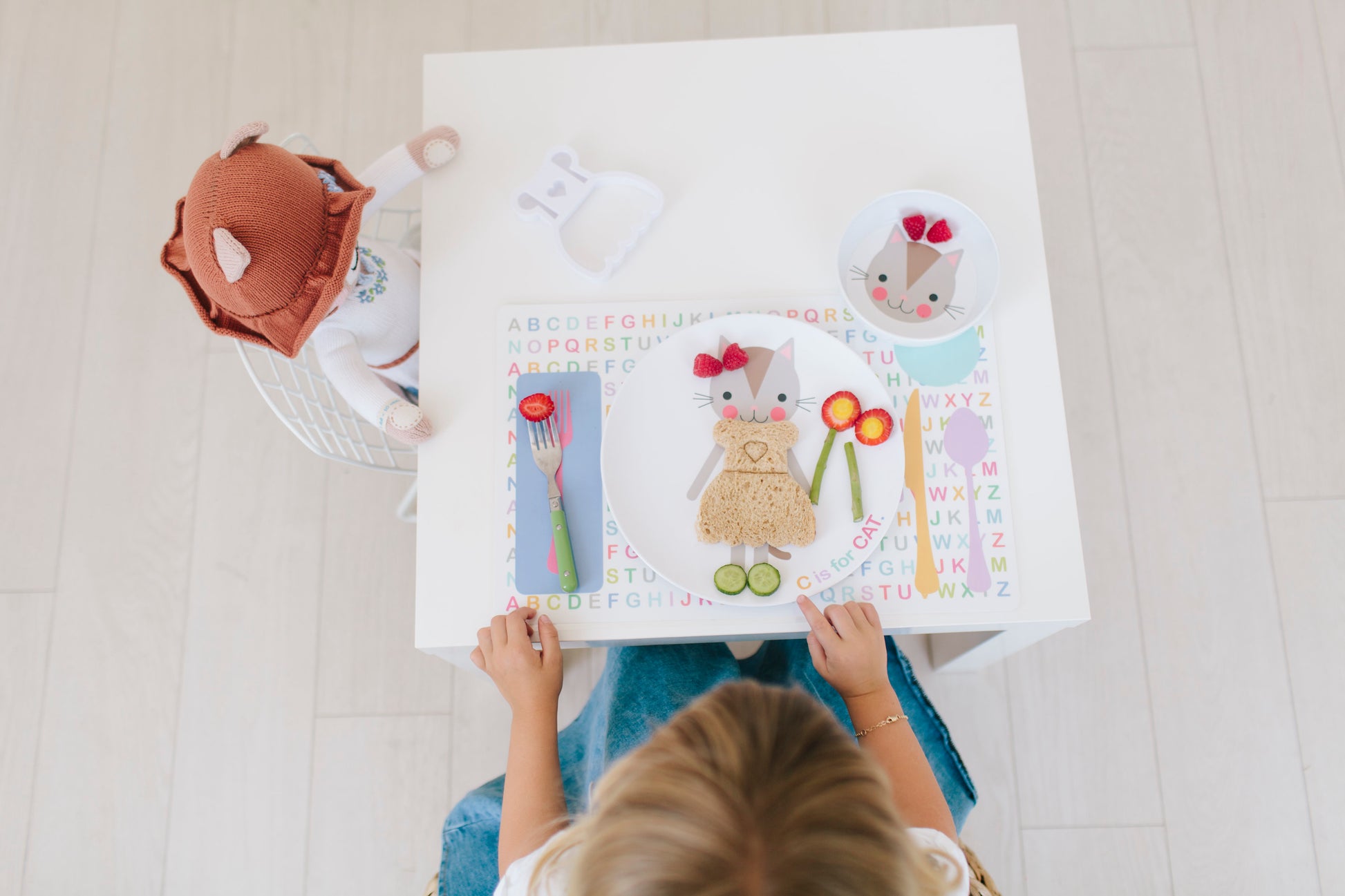 Little girl with her stuffed animal cat and personalized Dylbug Cat dish set including cat plate, cat bowl and cat placemat perfect for tea parties and making every meal time fun