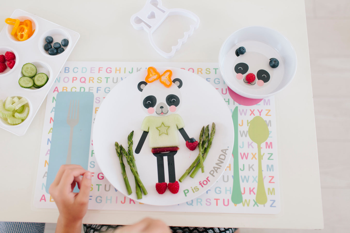 Dylbug Custom Panda Dish Set for kids including Panda plate, Panda bow, and panda placemat. Child dressing up their panda plate with healthy fun making meal time fun and creative.