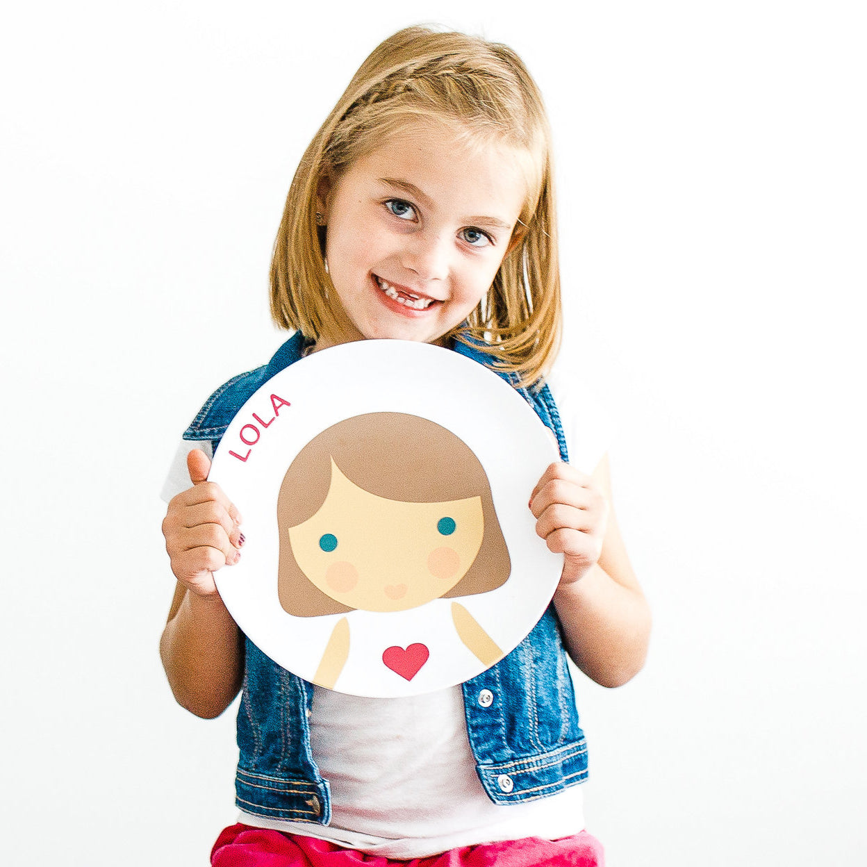 Little girl holding up her personalized Dylbug face plate in pink.
