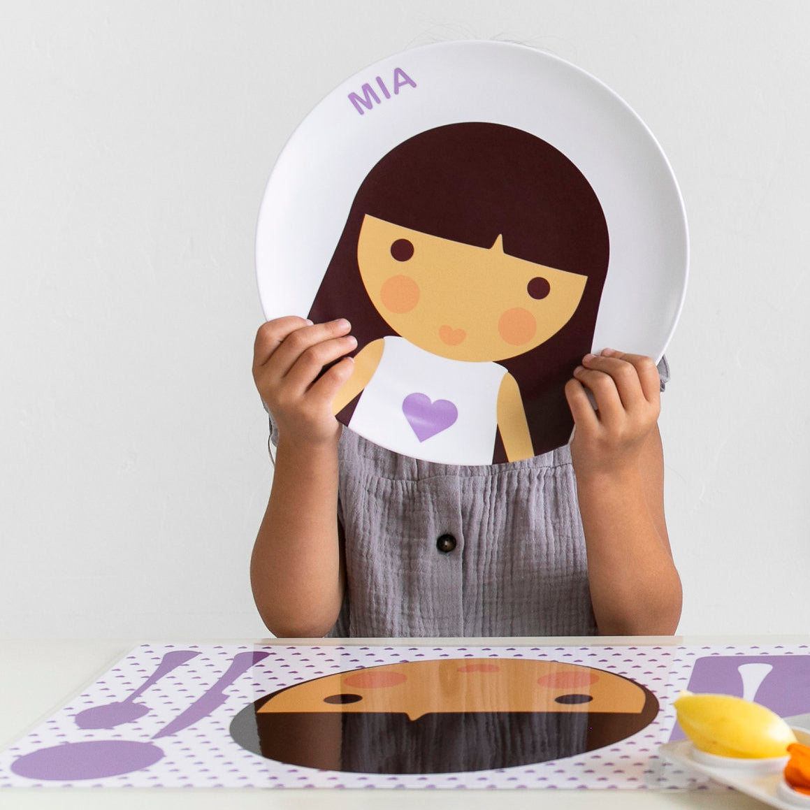 Little girl holding up her personalized Dylbug face plate in purple.