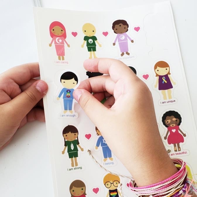Little girl using her Harmony Kids Sticker Sheet - This sticker sheet has 16 positive and empowering affirmations for kids to help develop high self-esteem and confidence.