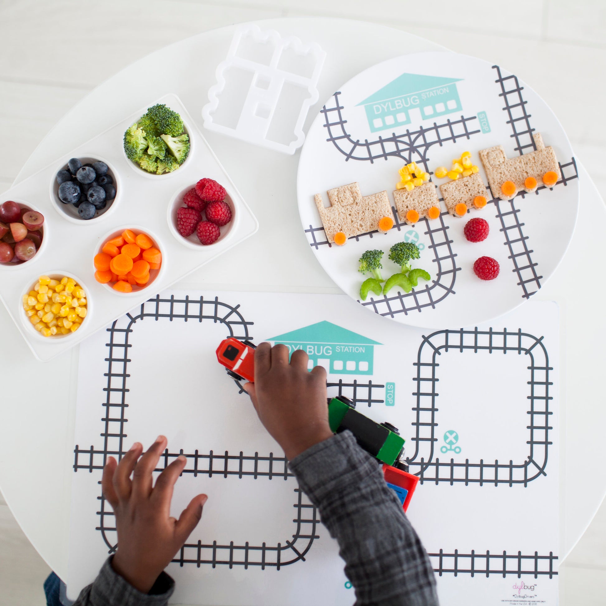 Children's Dish Sets - Little boy playing his Dylbug personalized train placemat in teal. creating a train sandwich using our custom train food cutter.