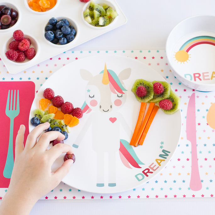 Child adding fruit to the food fashion creation using their Dylbug pink unicorn plate