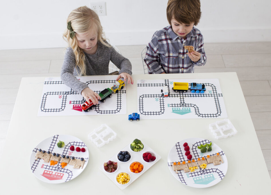 Little boy and little girl using the custom Dylbug train placemats, plates, and food cutter from our Drivers Collection. playing trains, making train sandwiches and making fun meal time memories