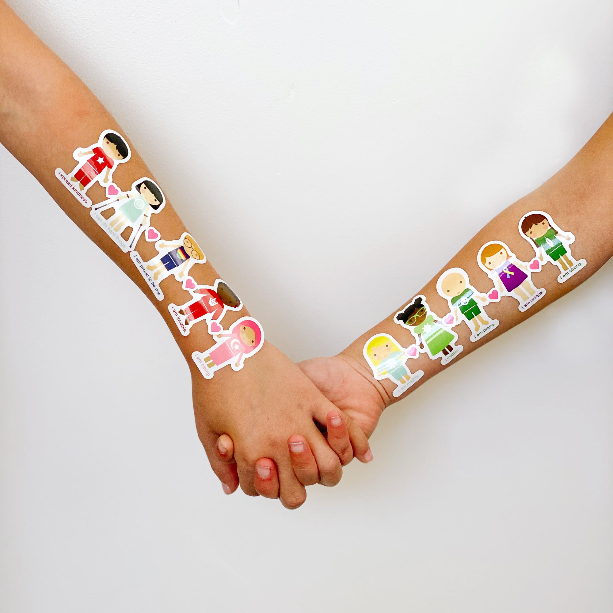 Two children holding hands with Dylbug Harmony stickers on their arms